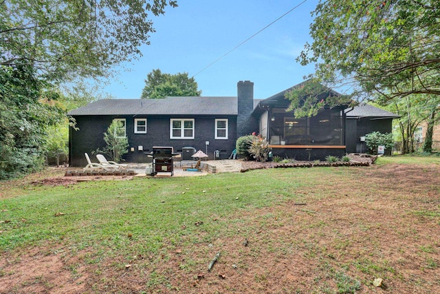 rear view of property featuring a sunroom, a patio area, and a yard