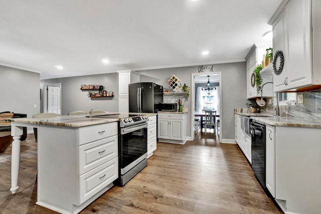 kitchen featuring white cabinets, black appliances, a kitchen bar, light hardwood / wood-style flooring, and decorative columns