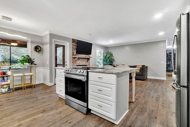 kitchen with appliances with stainless steel finishes, ornamental molding, light hardwood / wood-style floors, and white cabinetry