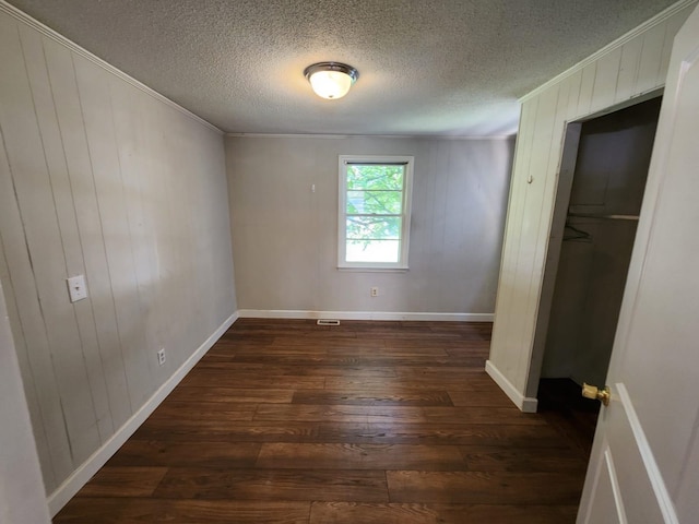 unfurnished bedroom featuring a textured ceiling, crown molding, and dark wood-type flooring