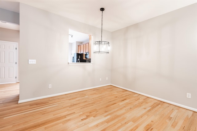 empty room featuring light wood-type flooring and a chandelier