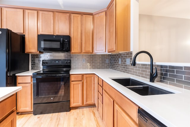 kitchen featuring black appliances, light hardwood / wood-style floors, sink, and tasteful backsplash