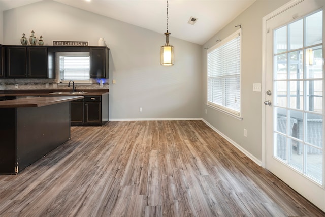 kitchen with wood-type flooring, pendant lighting, lofted ceiling, and tasteful backsplash