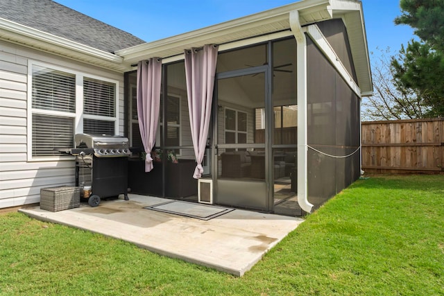 rear view of property with a sunroom, a patio area, and a lawn