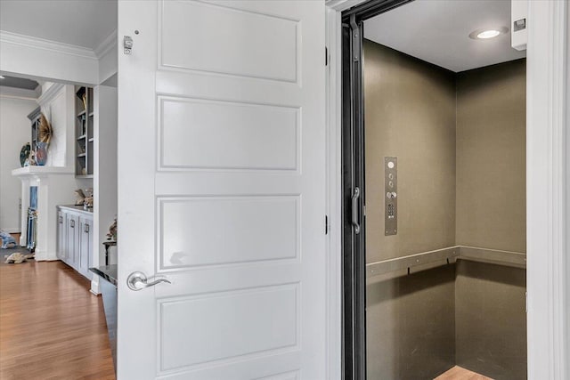 interior space with baseboards, elevator, crown molding, and wood finished floors