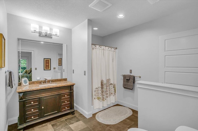 bathroom with vanity, baseboards, a textured ceiling, a shower with curtain, and visible vents