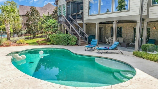 view of pool with a patio, a fenced in pool, fence, and stairs