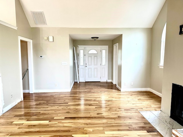 foyer with a healthy amount of sunlight, a tile fireplace, and light hardwood / wood-style floors