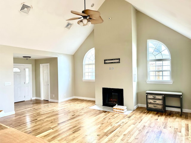 unfurnished living room with high vaulted ceiling, light hardwood / wood-style floors, and ceiling fan