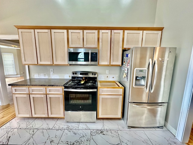 kitchen with light wood-type flooring, dark stone counters, light brown cabinets, and stainless steel appliances