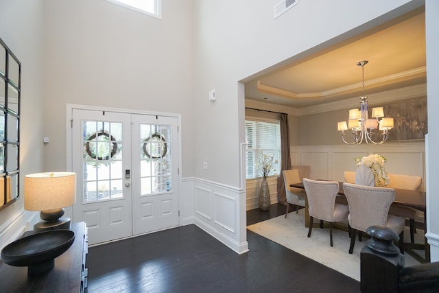 entryway featuring french doors, dark wood-type flooring, an inviting chandelier, and a healthy amount of sunlight