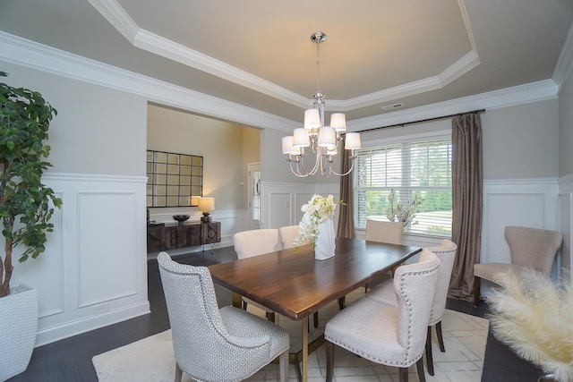 dining area featuring a raised ceiling, ornamental molding, an inviting chandelier, and dark wood-type flooring