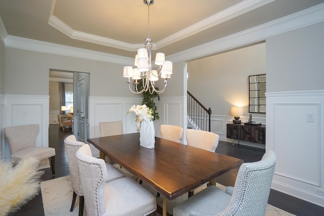 dining space featuring a notable chandelier, a raised ceiling, and ornamental molding