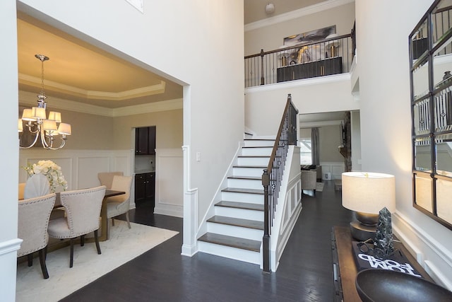 entrance foyer with dark wood-type flooring, crown molding, and a chandelier