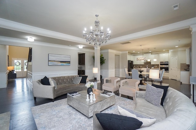 living room with an inviting chandelier, decorative columns, dark hardwood / wood-style floors, and crown molding