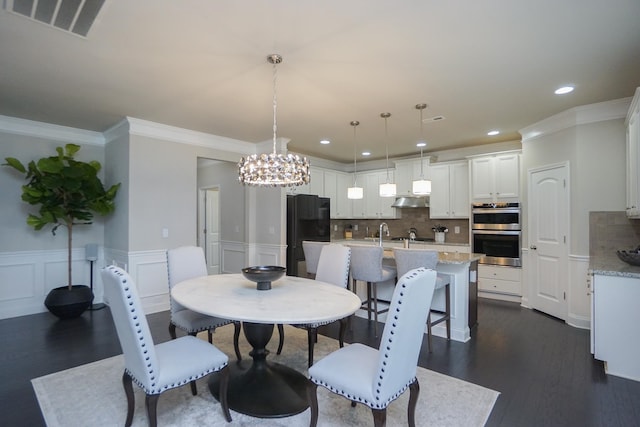 dining room featuring crown molding, dark hardwood / wood-style flooring, a chandelier, and sink