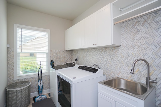 washroom featuring cabinets, sink, washing machine and clothes dryer, and a healthy amount of sunlight