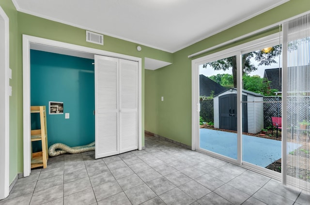 unfurnished bedroom featuring ornamental molding, a closet, access to exterior, and light tile patterned flooring