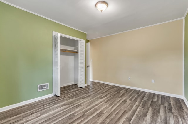 unfurnished bedroom with a closet, hardwood / wood-style flooring, and crown molding