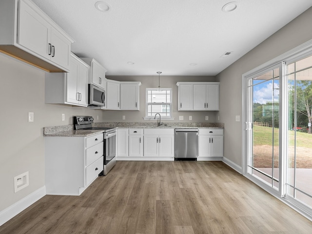 kitchen featuring light hardwood / wood-style floors, white cabinetry, pendant lighting, stainless steel appliances, and sink