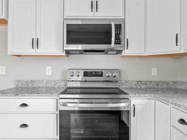 kitchen with appliances with stainless steel finishes, light stone counters, and white cabinets