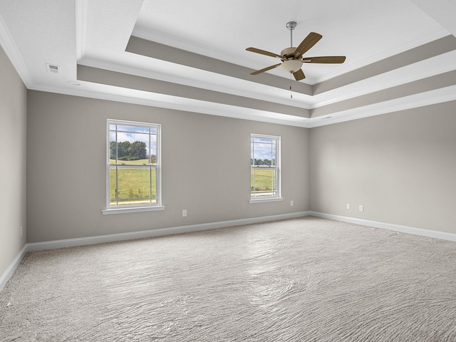 carpeted spare room with ceiling fan, a tray ceiling, and ornamental molding