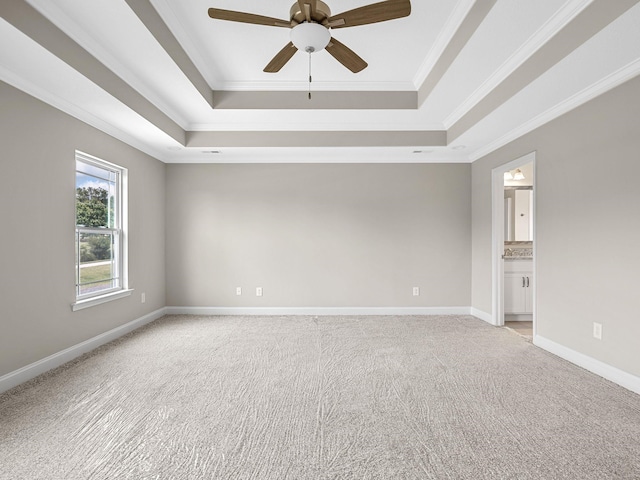 carpeted spare room with a raised ceiling, ornamental molding, and ceiling fan