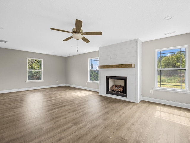 unfurnished living room featuring light hardwood / wood-style flooring, a wealth of natural light, ceiling fan, and a fireplace