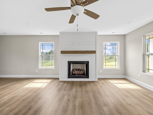 unfurnished living room featuring light wood-type flooring, a fireplace, and ceiling fan