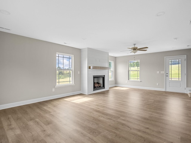 unfurnished living room with light hardwood / wood-style flooring, ceiling fan, and a fireplace