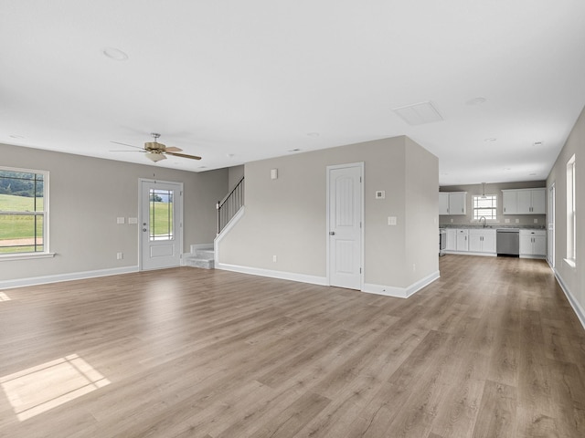 unfurnished living room with light hardwood / wood-style floors, sink, and ceiling fan