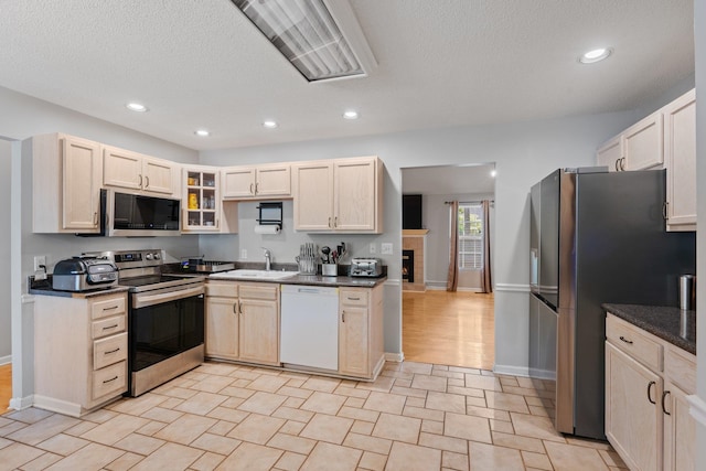 kitchen with stainless steel appliances, light hardwood / wood-style floors, a textured ceiling, and sink