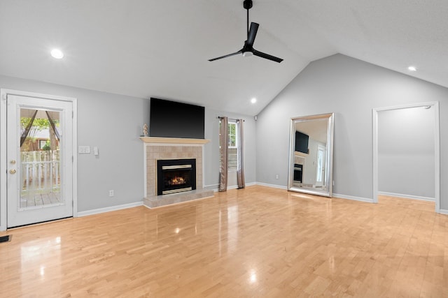 unfurnished living room with lofted ceiling, ceiling fan, a tile fireplace, and plenty of natural light