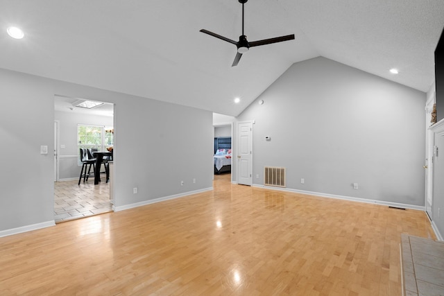 unfurnished living room with a textured ceiling, high vaulted ceiling, ceiling fan, and light hardwood / wood-style flooring