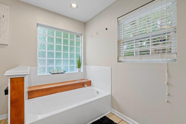 bathroom featuring a textured ceiling, a tub to relax in, and tile patterned floors