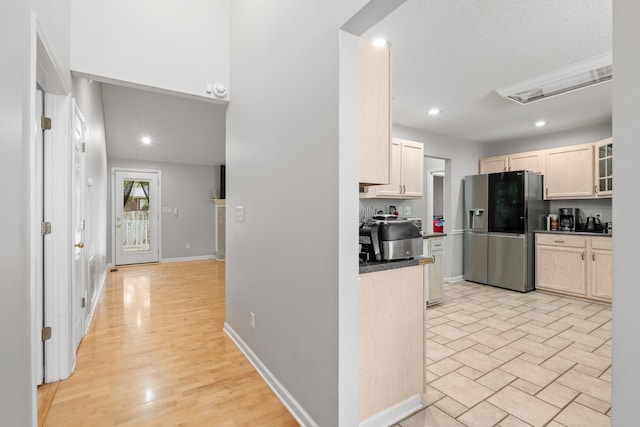 kitchen with light wood-type flooring, stainless steel fridge, and a textured ceiling