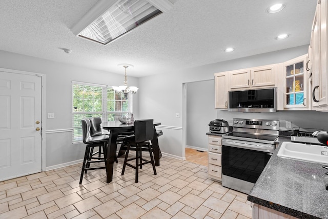 kitchen featuring appliances with stainless steel finishes, a textured ceiling, decorative light fixtures, sink, and a chandelier