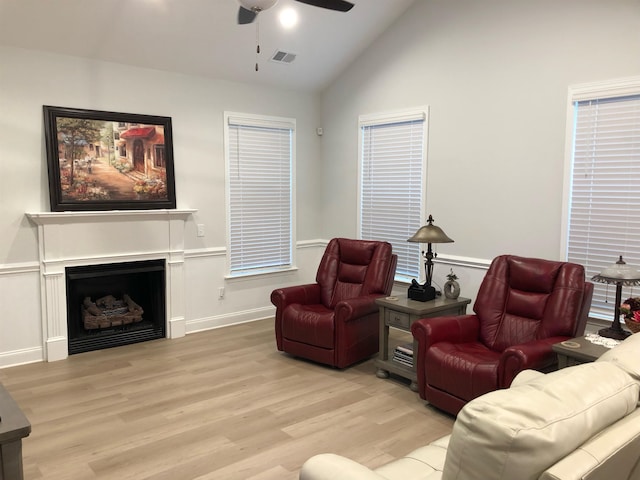 living room with ceiling fan, light hardwood / wood-style floors, and high vaulted ceiling