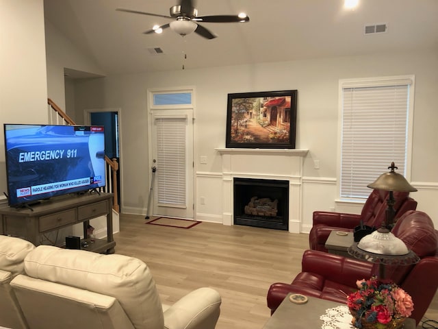 living room with ceiling fan, light wood-type flooring, and vaulted ceiling