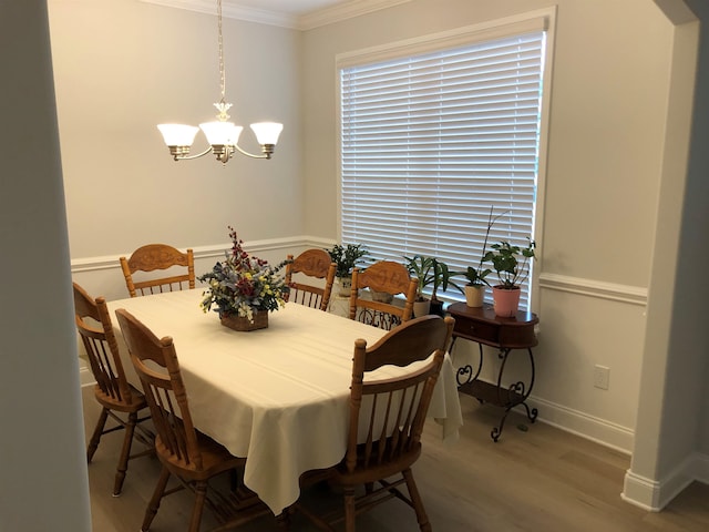 dining space with wood-type flooring, an inviting chandelier, and crown molding