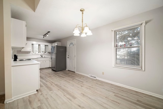 kitchen featuring sink, a notable chandelier, white cabinets, stainless steel refrigerator, and light hardwood / wood-style flooring