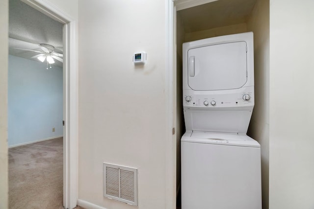 laundry room featuring ceiling fan, light carpet, and stacked washer / drying machine