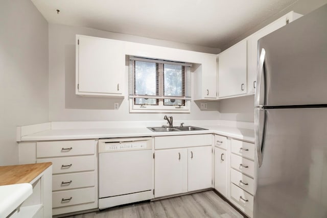 kitchen featuring dishwasher, light hardwood / wood-style floors, sink, white cabinetry, and stainless steel fridge