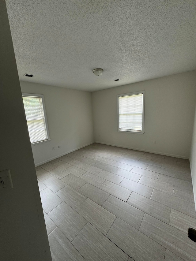 unfurnished room with a textured ceiling and plenty of natural light