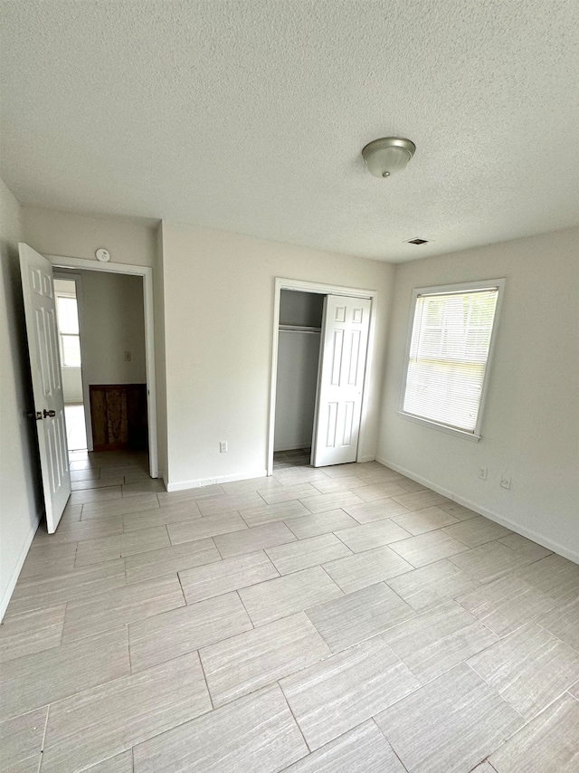 unfurnished bedroom with a textured ceiling and a closet