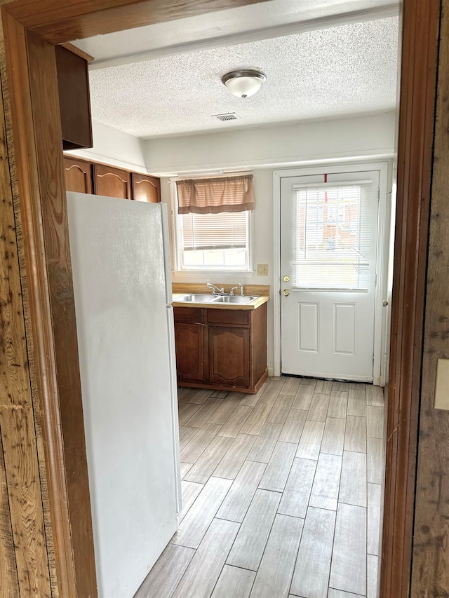 kitchen featuring white refrigerator, sink, and a textured ceiling