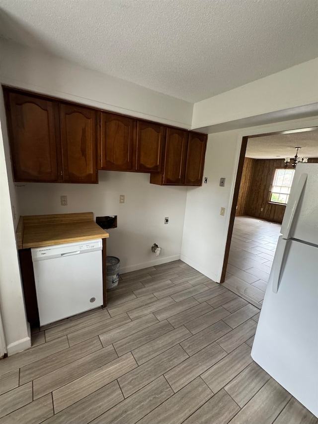 kitchen featuring white appliances, a textured ceiling, and dark brown cabinetry