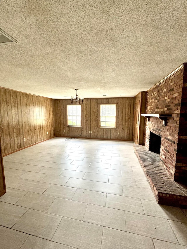 unfurnished living room with a brick fireplace, a textured ceiling, and wooden walls