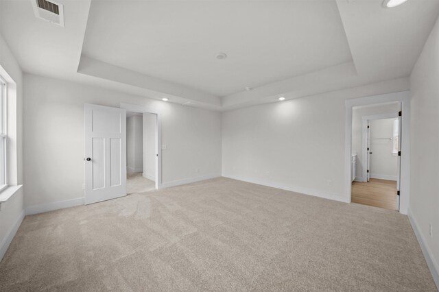 carpeted empty room with a tray ceiling