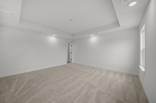 empty room with light carpet and a raised ceiling